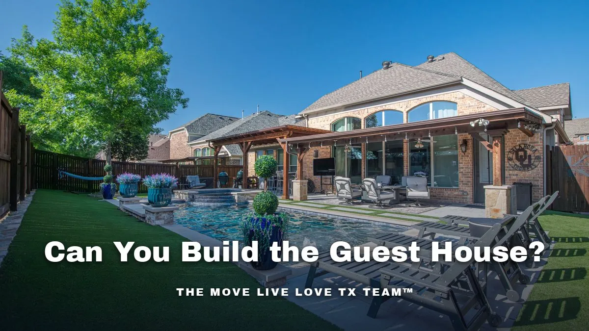 A detached guest house with large windows behind a main luxury home, surrounded by mature landscaping in daylight