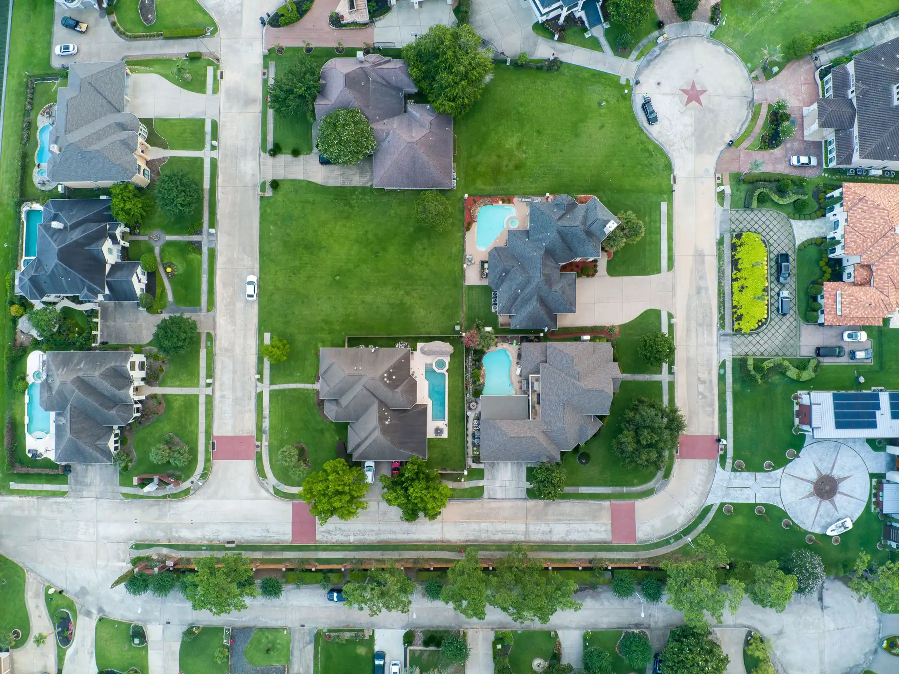 Aerial drone view of a Houston-area neighborhood, tree-lined streets and pools