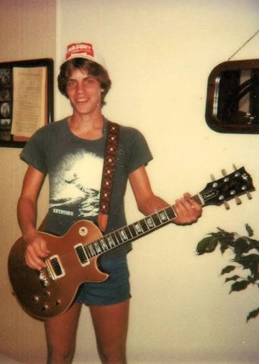 Peter Royster as a teenager in Clear Lake, smiling and holding an electric guitar