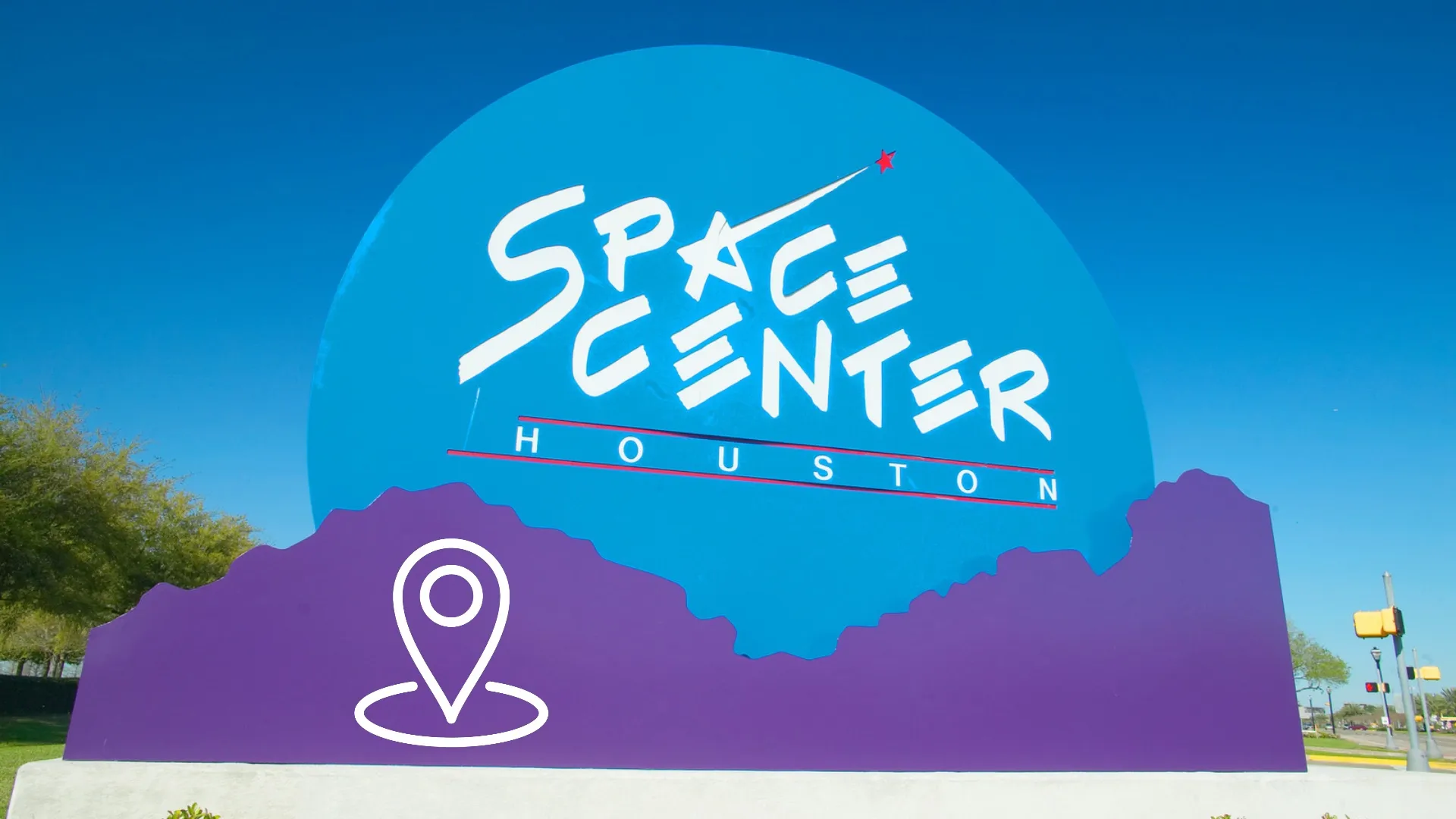 The blue and purple Space Center Houston entrance sign under a clear sky, with a map pin graphic