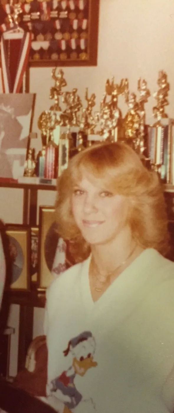 Vicky Royster as a teenager in Clear Lake, standing in front of a shelf of trophies